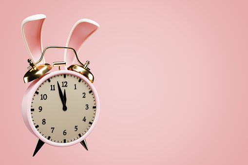 Easter concept. Alarm clock in rabbit ears on a pink background. 3d rendering
