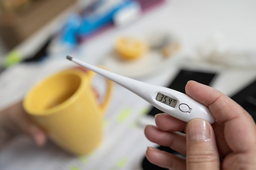 Shot of a woman holding a digital thermometer