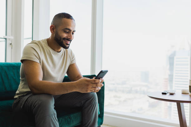 istock Cheerful bearded man looking at cellphone in modern apartment 1458834431