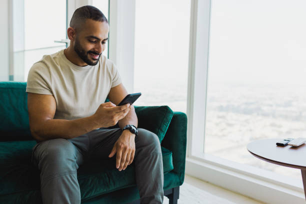 istock Happy bearded man looking at cellphone on couch 1458834436