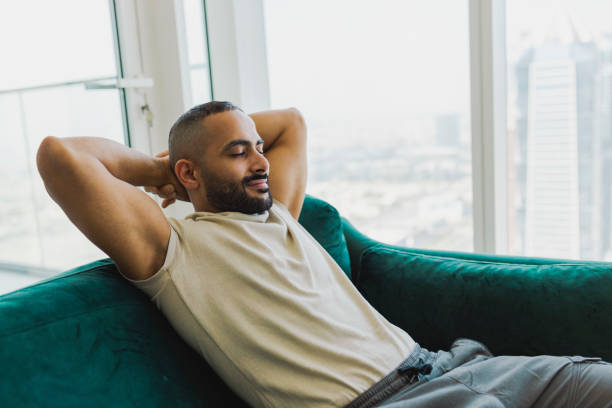 istock Bearded man relaxing on couch with eyes closed in modern apartment 1458834470