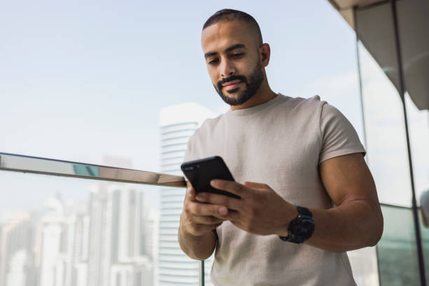 istock Bearded man looking at cellphone on apartment balcony 1458834497
