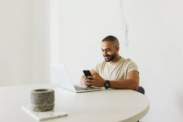 istock Man with beard texting on cellphone at desk in home office 1458834542