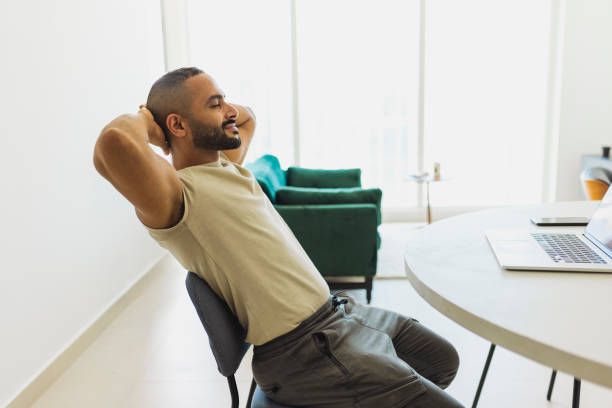 istock Side view of bearded man relaxing with hands behind head in modern home office 1458834544