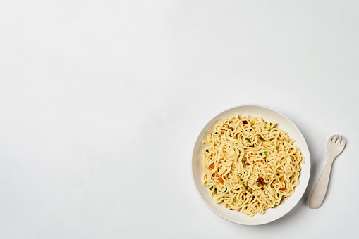 Instant noodles composition. Noodles and fresh vegetables and spices on white background