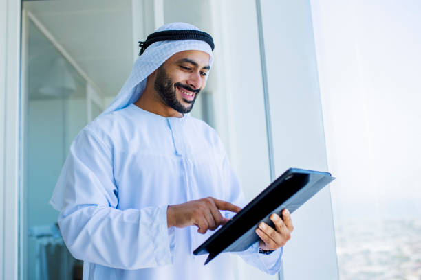 istock Cheerful Arab businessman using digital tablet beside office window 1458836108