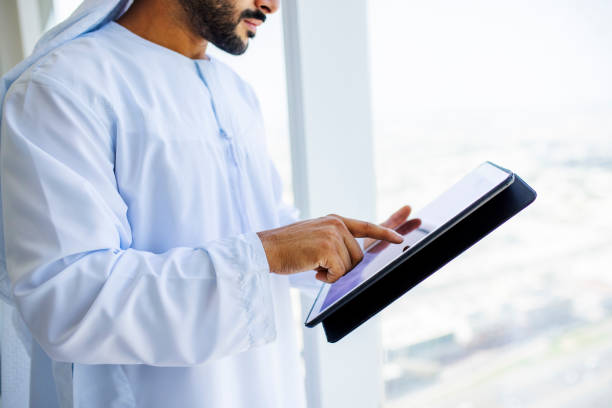 Close-up of Arab businessman using digital tablet beside window stock photo