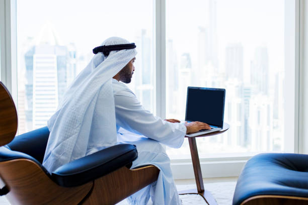 istock Side view of bearded Arab businessman working on laptop in modern office 1458836155