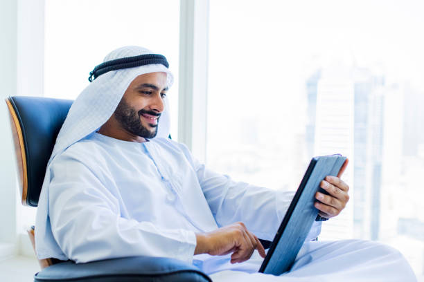 istock Cheerful Arab businessman with beard using digital tablet on armchair in office 1458836184
