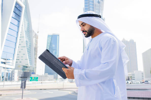 istock Side view of Arab businessman with beard using digital tablet in city centre 1458836192