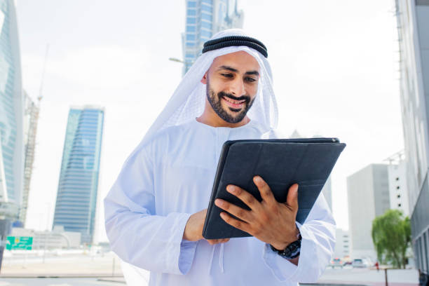 istock Cheerful Arab businessman with beard looking at digital tablet in city centre 1458836204