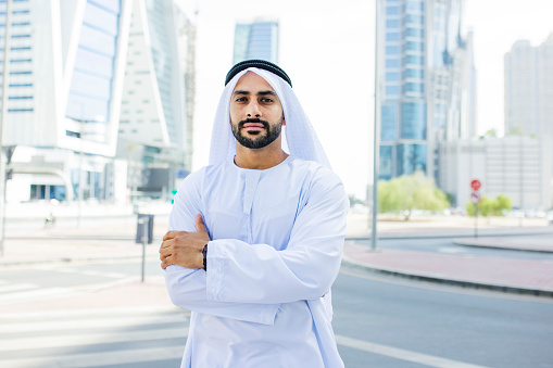Bearded Arab businessman wearing kandora, crossing arms and looking at camera on the streets in city centre