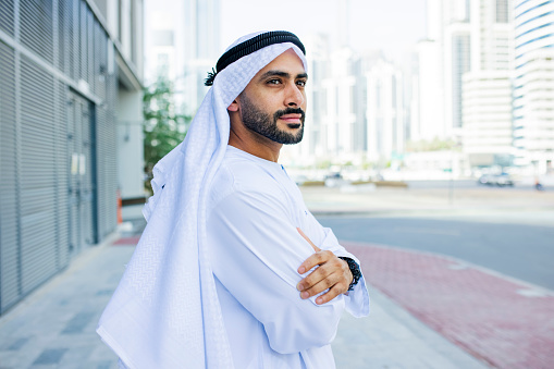 Vista lateral de un hombre de negocios árabe barbudo mirando a lo lejos en el pavimento photo