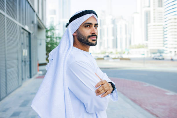 Side view of bearded Arab businessman looking into distance on pavement stock photo