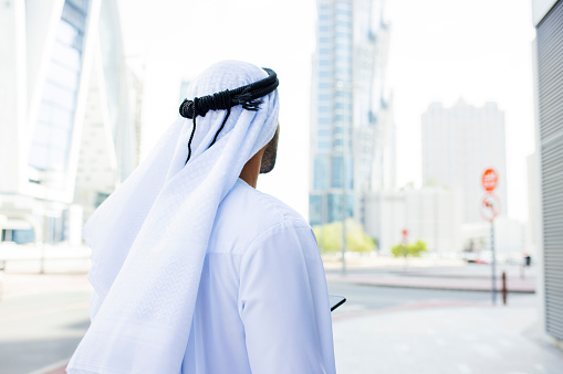 Arab man looking into distance on pavement in city centre