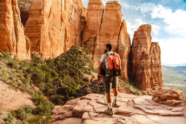 hombre aventurero con una mochila caminando por el cañón en el suroeste de américa - sedona fotografías e imágenes de stock