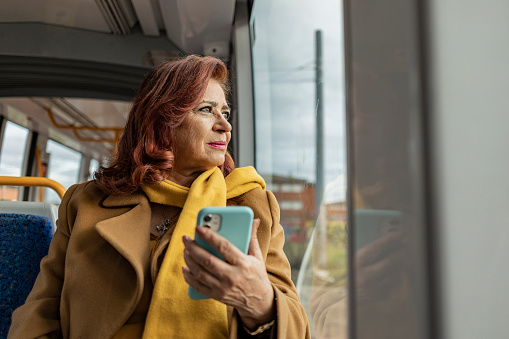 pretty mature woman using mobile phone while traveling on the train. look through the window