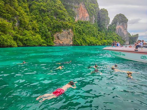 People snorkeling in the deep clear blue Andaman sea near Phi Phi island in Thailand