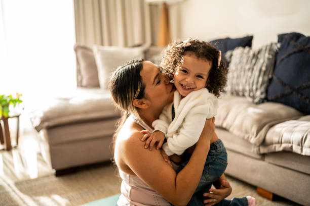 retrato de una niña pequeña divirtiéndose con su madre en la sala de estar de su casa - familia con un hijo fotografías e imágenes de stock