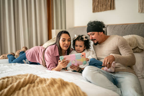 istock Parents using digital tablet with their daughter in the bedroom at home 1458845549
