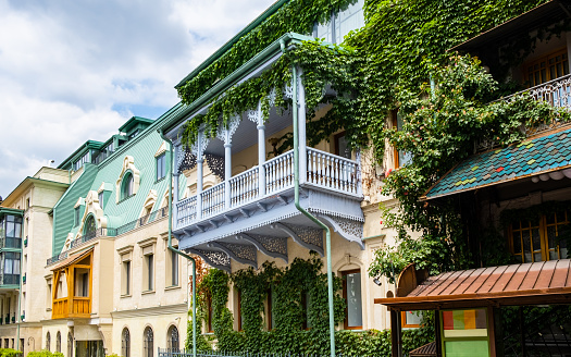 Carved wooden balcony and colorful buildings in historical Tbilisi, Georgia. Traditional decoration of Georgian house in Tiflis old town. Ivy on wall.