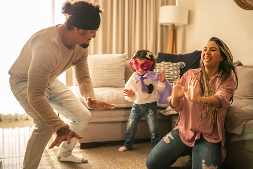 Parents dancing with their daughter in the living room at home