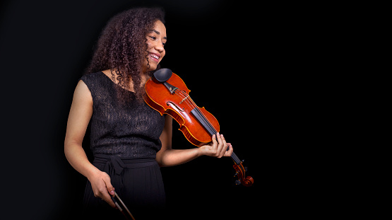 Classical music concept. Young woman violinist smiling with her violin. Copyspace.