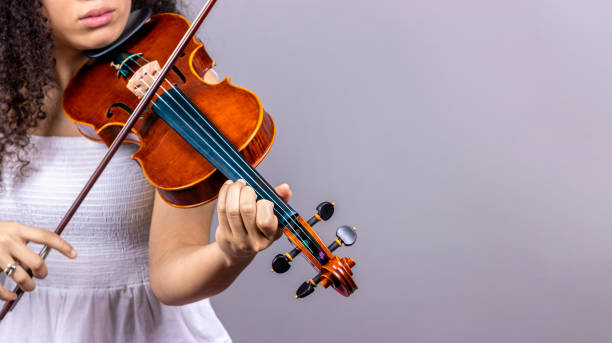 istock Classical music concept. Copyspace. Young girl plays violin on grey background. 1458849482