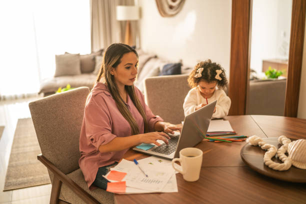 istock Young woman working while her daughter draws beside her at home 1458849744