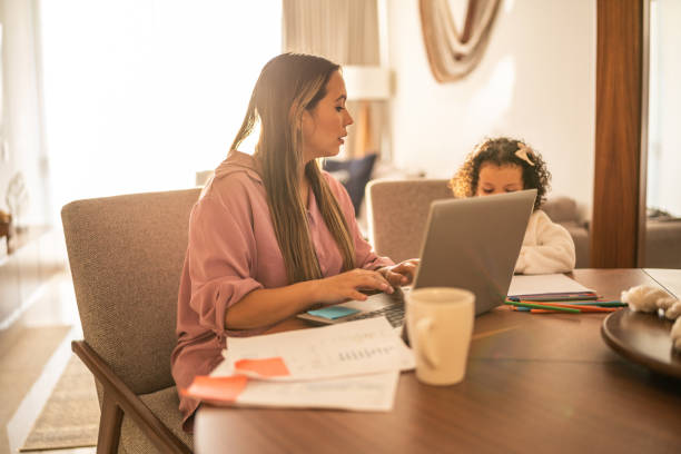 istock Young woman working while her daughter draws beside her at home 1458849766