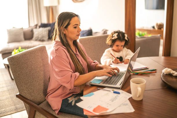istock Young woman working while her daughter draws beside her at home 1458850097