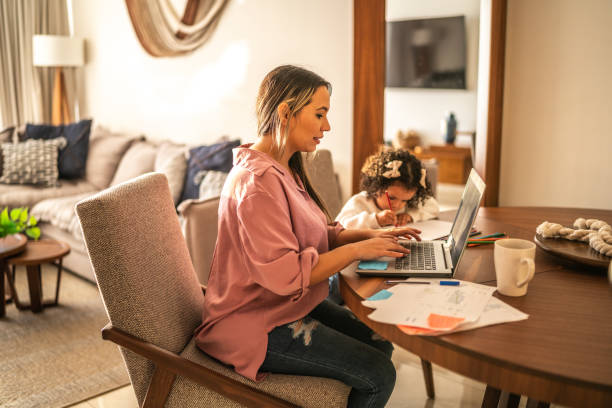 istock Young woman working while her daughter draws beside her at home 1458850146
