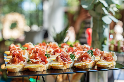 catering buffet table with snacks and appetizers. Set of canapÃ©s with jamon, bruschetta, pear and cheese and mint