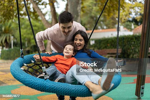 istock Family playing on the swing in the park 1458851877