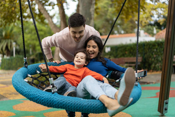 Family playing on the swing in the park stock photo
