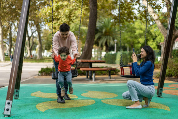 istock Father playing with his son on the swing in the park 1458852072