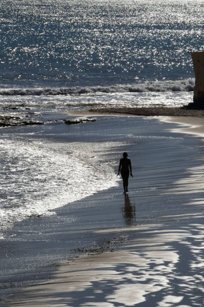 Against the rhythmic patterns of the pergola man with backpack standing, absorbing the calm energy of the sea