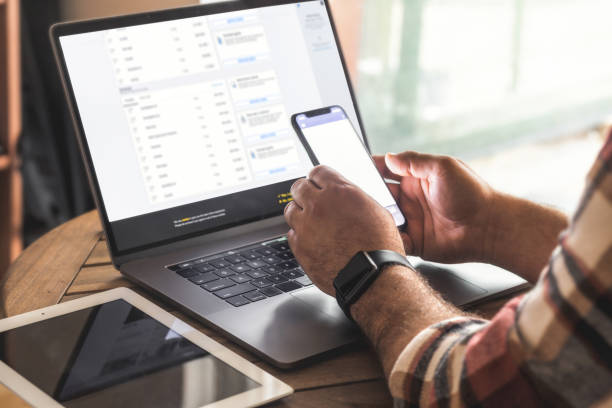 istock Male freelancer or entrepreneur working from home using laptop and mobile phone. Remote online work, safe internet banking 1458856380
