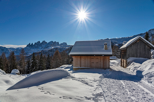 Mountain huts on a sunny winter day of Fuciade basin with Pala group on background,  Fassa Valley,  Italy