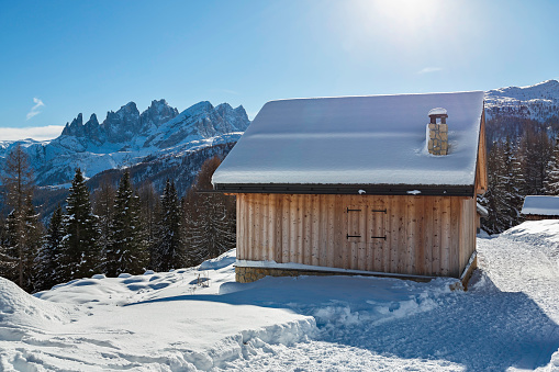 Mountain huts in the whiteness of the snow of Fuciade basin with Pala group on background,  Fassa Valley,  Italy