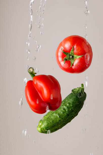 istock tomato, pepper, cucumber in a splash of water on a light background 1458859406