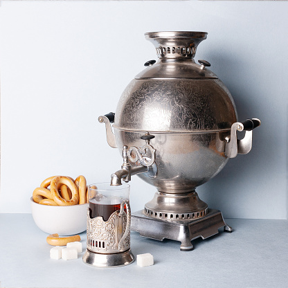 a glass of tea in a metal cup holder, bagels, a samovar, on the table