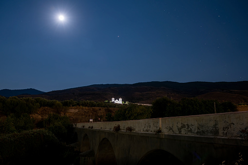 Hermitage of the Holy Martyrs, illuminated in the middle of the mountain, moon in the sky.