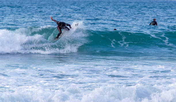 handsome young rider in a blue suit - riding a wave in tel aviv in sunny israel - sailboat sunset tel aviv sea imagens e fotografias de stock