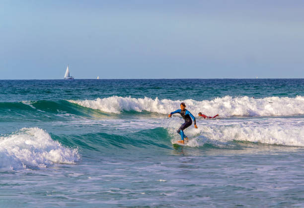 handsome young rider in a blue suit - riding a wave in tel aviv in sunny israel - sailboat sunset tel aviv sea imagens e fotografias de stock