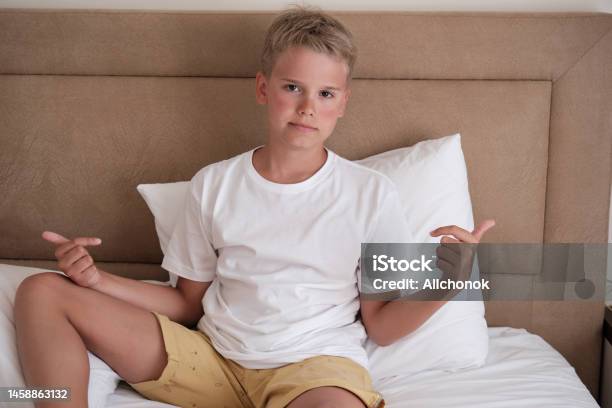Welche Gesichtspflege Für 12 Jährige Jungs Ein Süßer Junger Teenager Sitzt In Einem Weißen Tshirt Im Bett Und