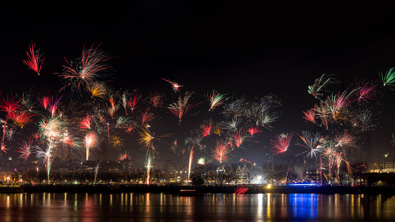 Cologne, Germany - 1.1.2023: Cologne old town is a popular location to celebrate New Years eve. Fireworks rise above historical buildings.