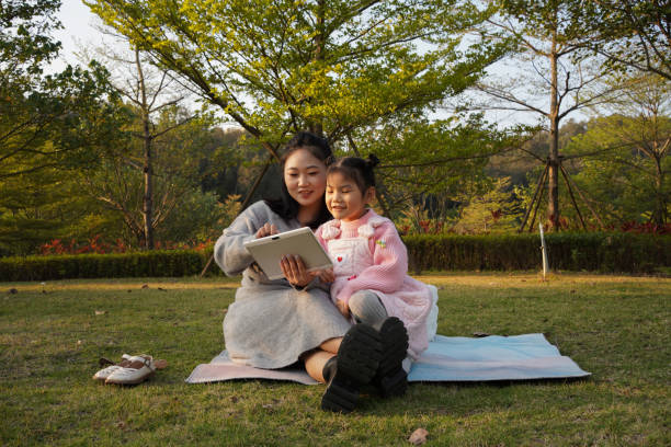 istock Cute little asian girl playing with tablet computer with her mother 1458874480