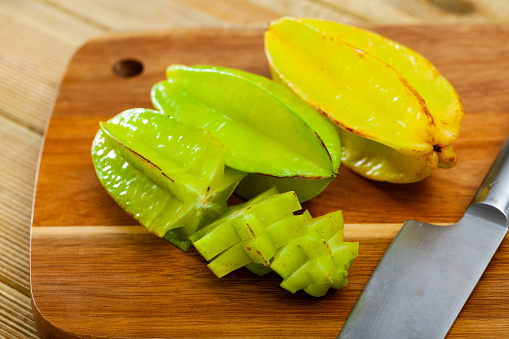 Whole and sliced fruits fresh carambola on wooden table. Healthy vegetarian ingredient