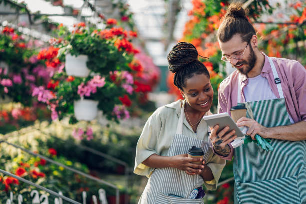 istock Multiracial florists working in a green house plant nursery and using tablet 1458876522